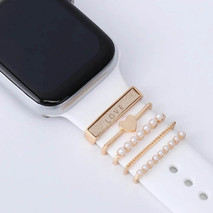 Elegant watch charm accessories featuring gold bands with heart and pearl designs, perfect for a stylish look.