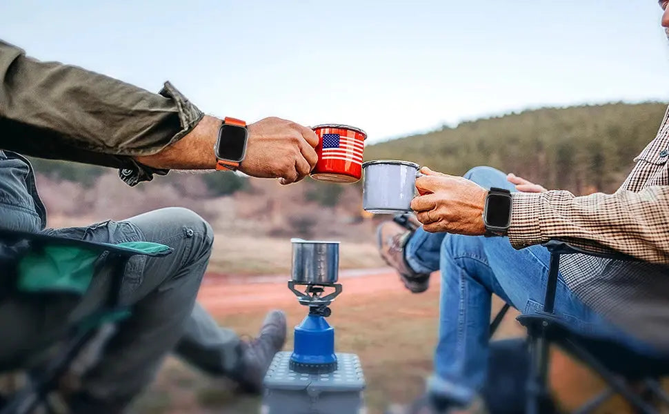 Two adventurers with Trekker bands on their Apple Watch Ultra 3, toasting mugs by a campfire.
