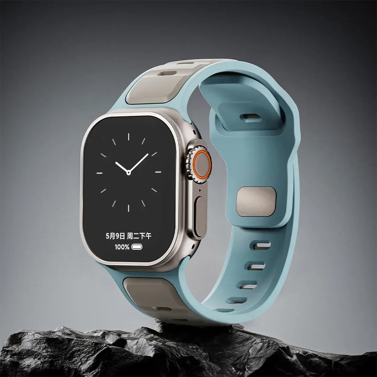 Trendy rugged silicon dual tone sports band for Apple Watch in blue and gray on a rock surface.