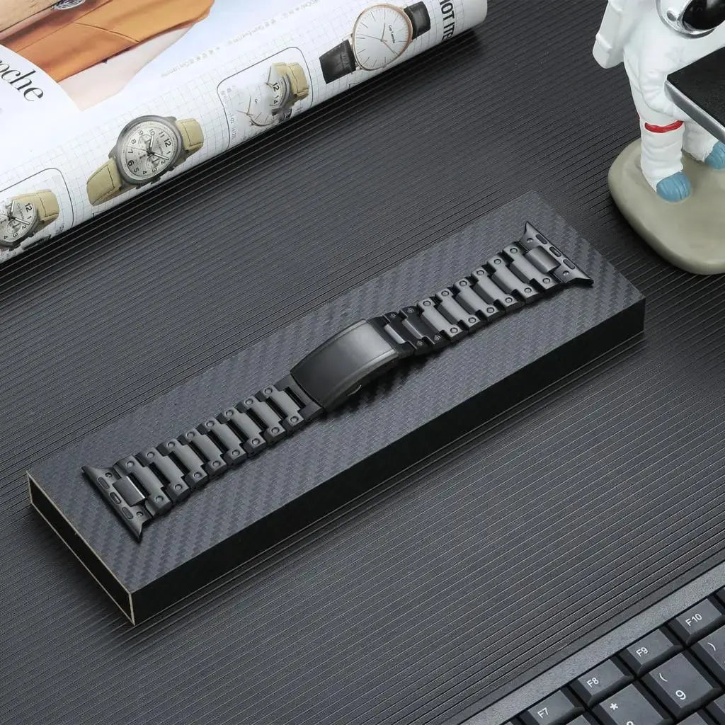 Glossy titanium bracelet for Apple Watch presented elegantly in a sleek black box on a stylish desk.