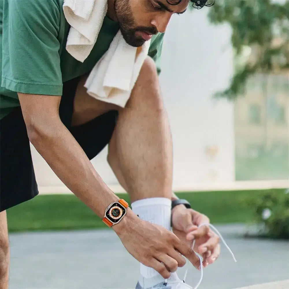 Man tying shoelaces wearing upgraded Rugged Alpine Loop watch, showcasing style and durability during outdoor activity.