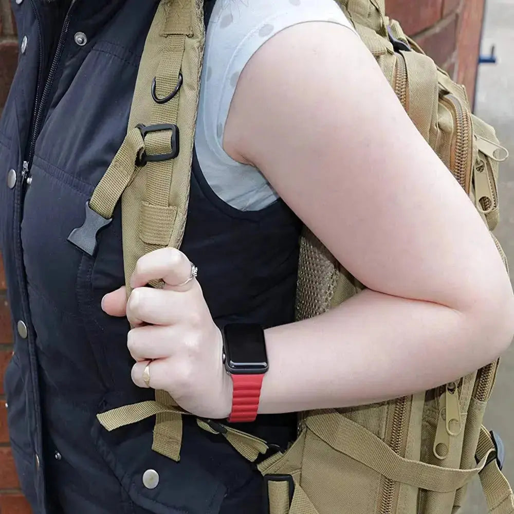 User wearing an Apple watch with a red band, holding a tactical backpack strap, showcasing adjustable leather loop design.