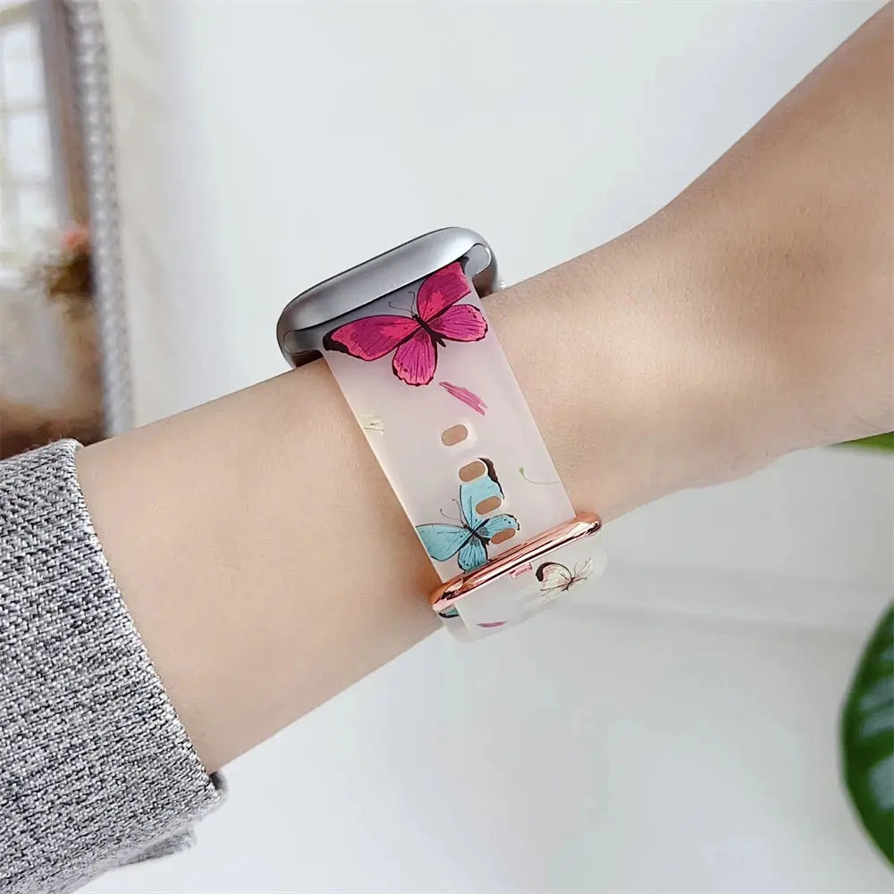 Clear silicone Apple Watch band with butterfly and flower design on wrist, showcasing a stylish and cute accessory.