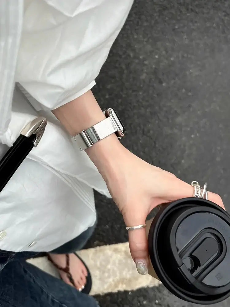 Glossy Stainless Steel Apple Watch Band – Slim Women’s Metal Strap (38–49mm) worn with a coffee cup in a casual setting.