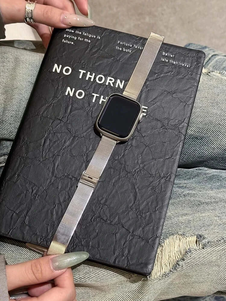 Glossy Stainless Steel Apple Watch Band – Slim Women’s Metal Strap (38–49mm) displayed on a notebook with casual attire.