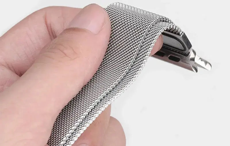 Close-up of a hand holding a sleek metal mesh loop bracelet, showcasing its smooth stainless steel texture and flexible design.