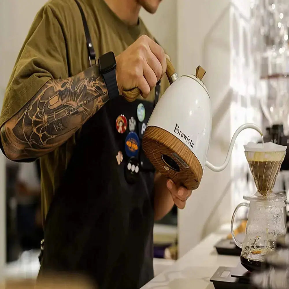 Person brewing coffee with a Brewista kettle, showcasing tattooed arm and Apple watch band for an enhanced coffee experience.