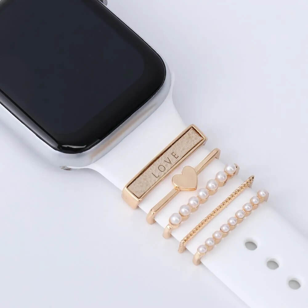 Elegant watch charm accessories featuring gold bands with heart and pearl designs, perfect for a stylish look.