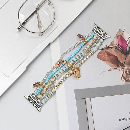 Beaded Apple Watch Band with Charms – Boho Bracelet Strap featuring vibrant beads and gold pendants on a table.
