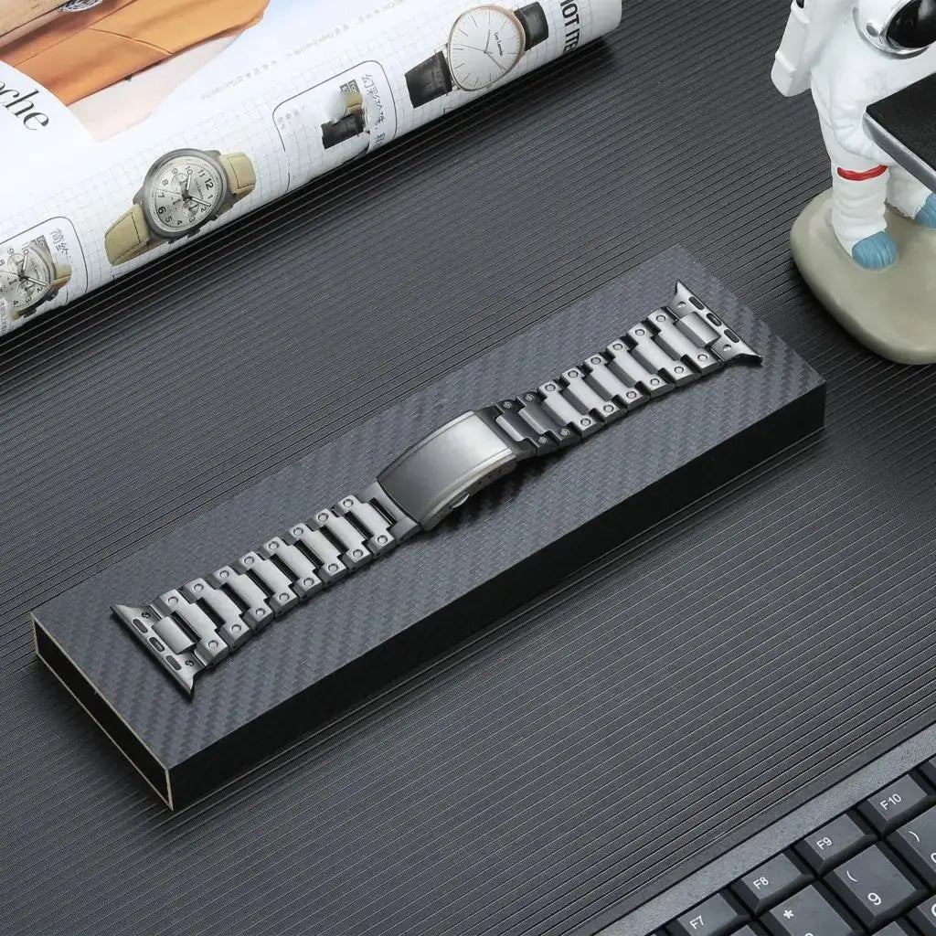 Glossy Titanium Bracelets for Apple Watch elegantly displayed in a black box on a stylish desk.