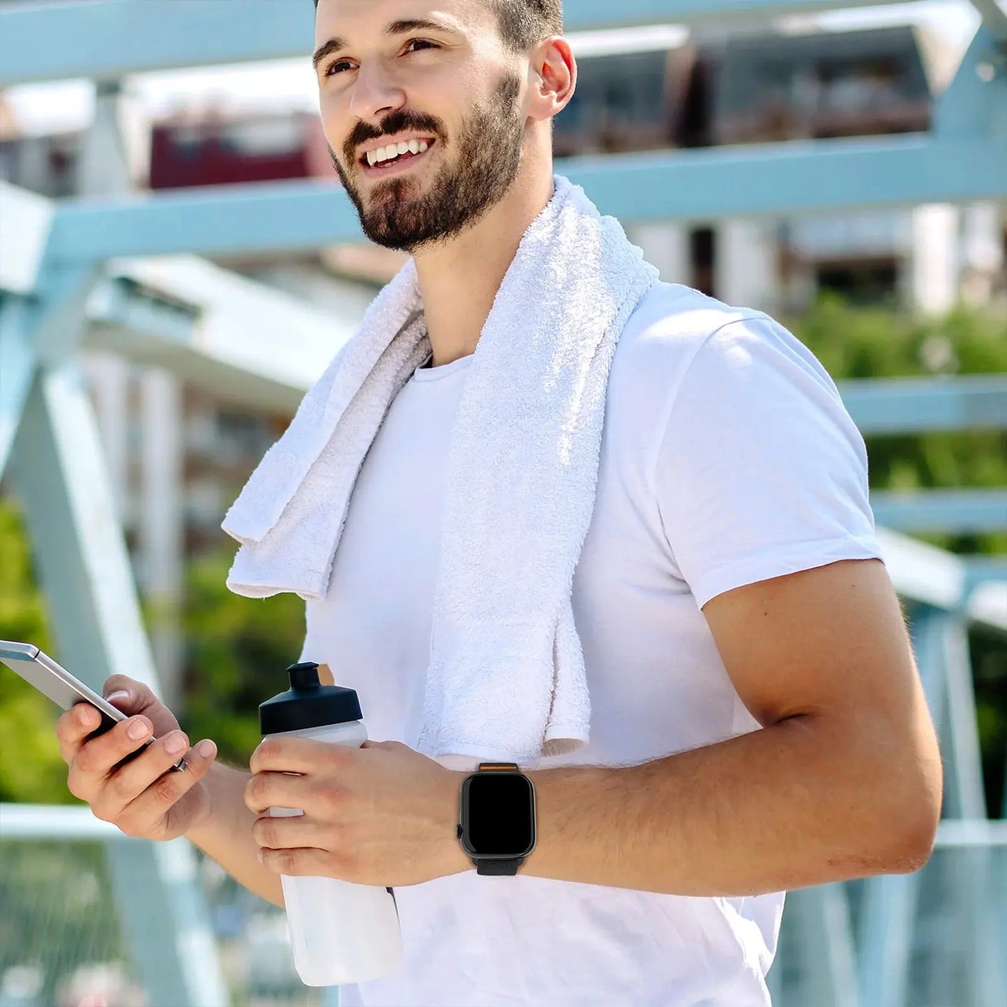 Athletic man wearing a smart watch with nylon elastic strap and titanium buckle, holding a water bottle and phone after workout.