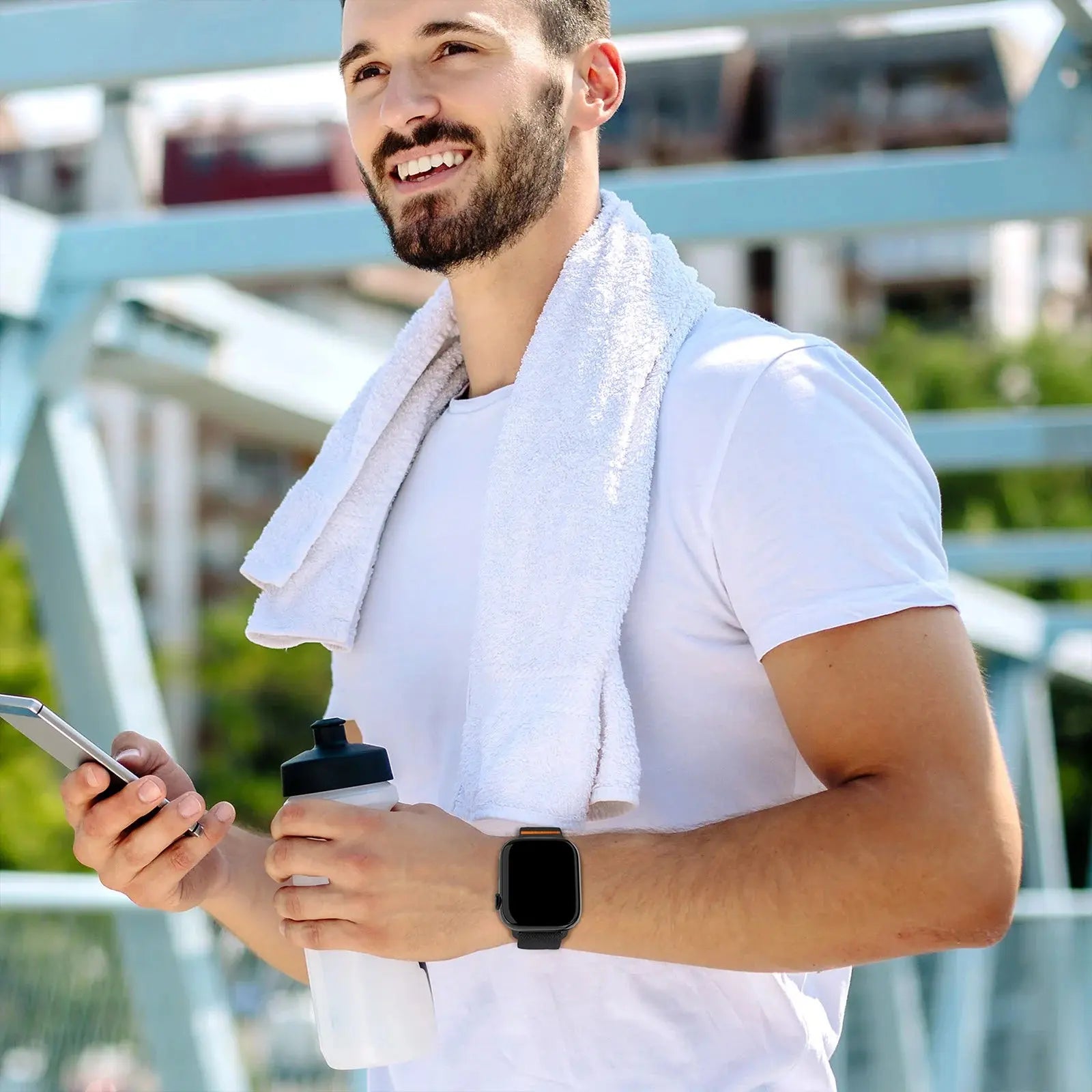 Athletic man wearing a smart watch with nylon elastic strap and titanium buckle, holding a water bottle and phone after workout.