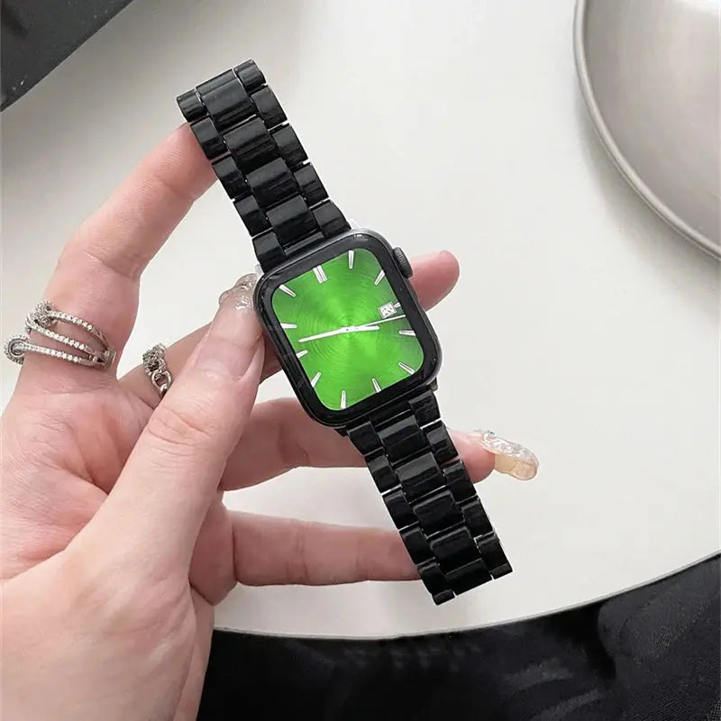 Hand holding a stylish black Apple Watch with green face, featuring a sleek design perfect for any outfit.