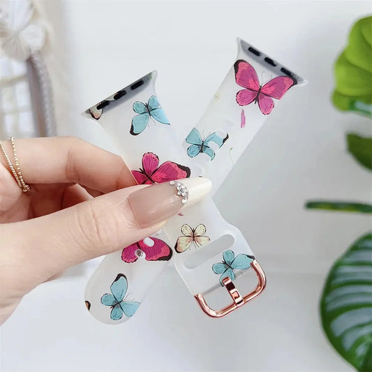 Clear silicone Apple Watch band with colorful flower and butterfly design held in hand.