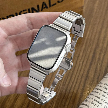 Hand holding the Dina stainless steel bracelet for Apple Watch, showcasing its elegant design and adjustable links.