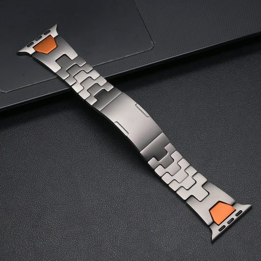 Ezra, The Premium Metal Apple Watch Band featuring stainless steel and an orange connection plate.