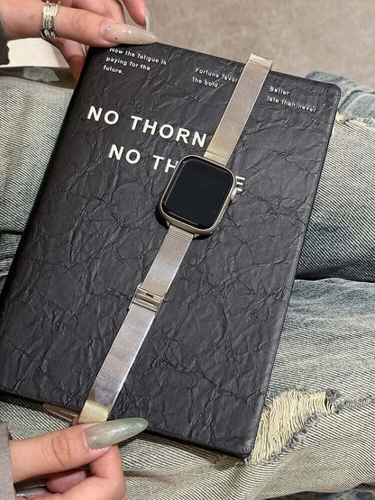 Glossy Stainless Steel Apple Watch Band – Slim Women’s Metal Strap (38–49mm) displayed on a notebook with casual attire.