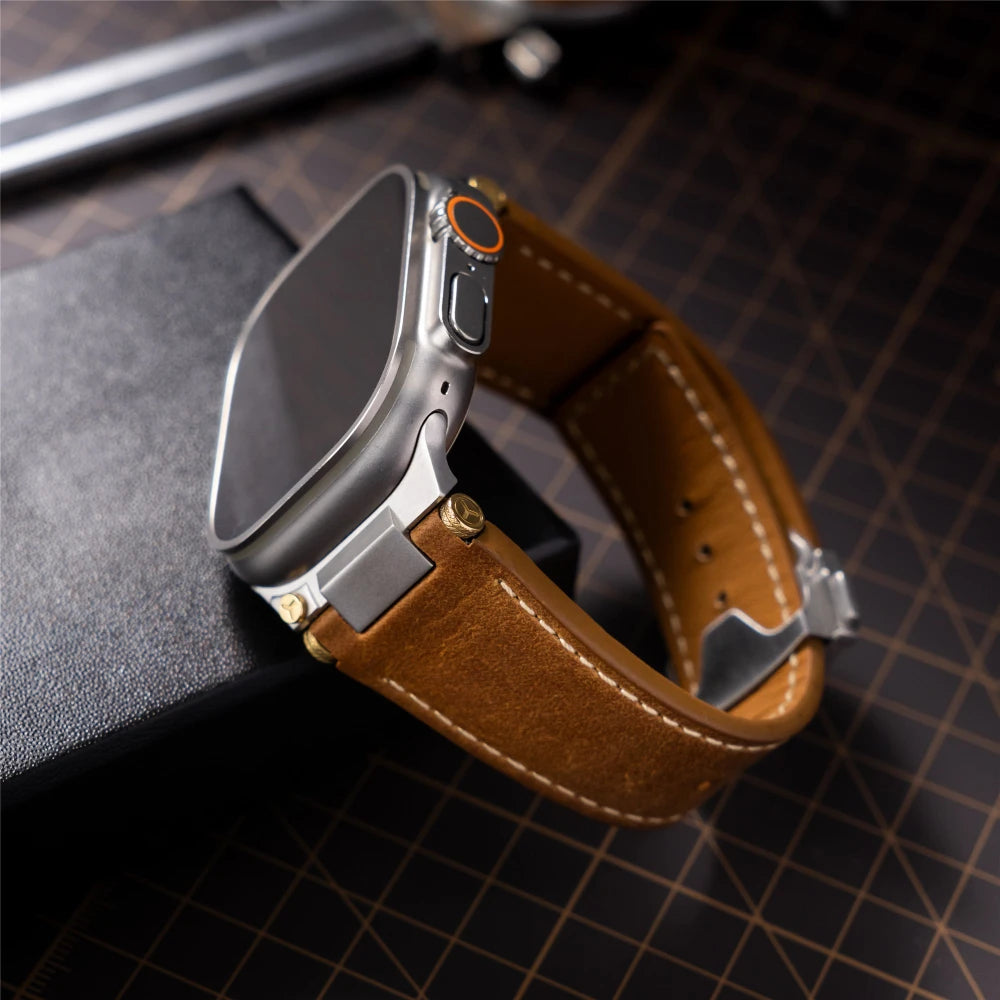 Luxury leather Apple Watch band for 49mm Ultra with premium brown leather, metal connectors, and refined stitching displayed in a professional desk setup