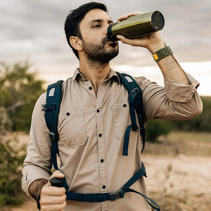 Man drinking from a bottle while wearing a tactical nylon loop band Apple Watch and outdoor gear.