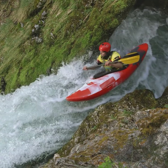 Kayaker navigating a rushing river in a red kayak, showcasing adventure and outdoor sports.