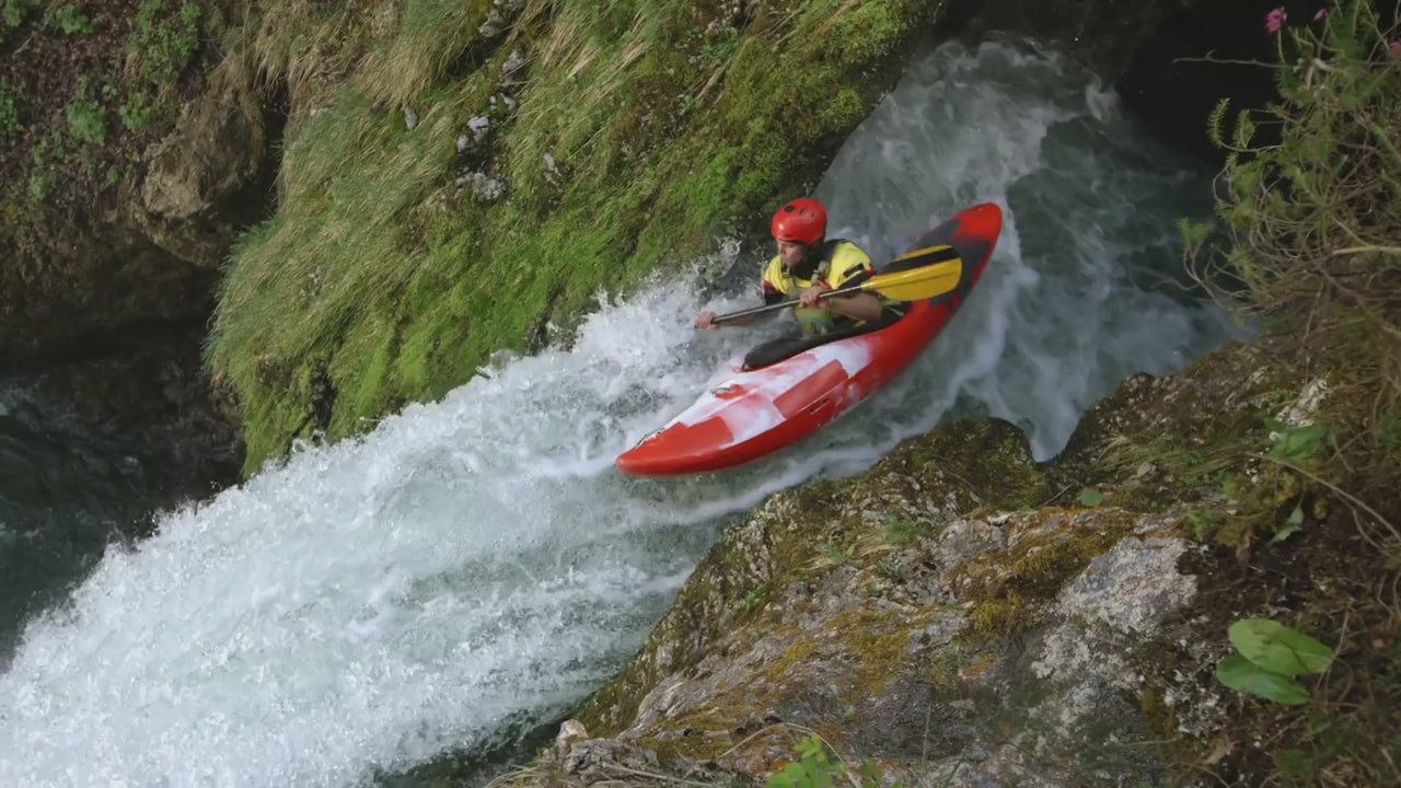 Kayaker navigating a rushing river in a red kayak, showcasing adventure and outdoor sports.