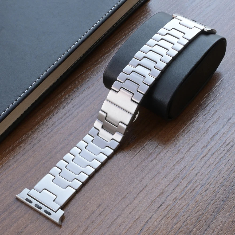Titanium Apple Watch Band Ultra 3/Series 11/SE – Luxury Bracelet on display with a black cushion and notebook.